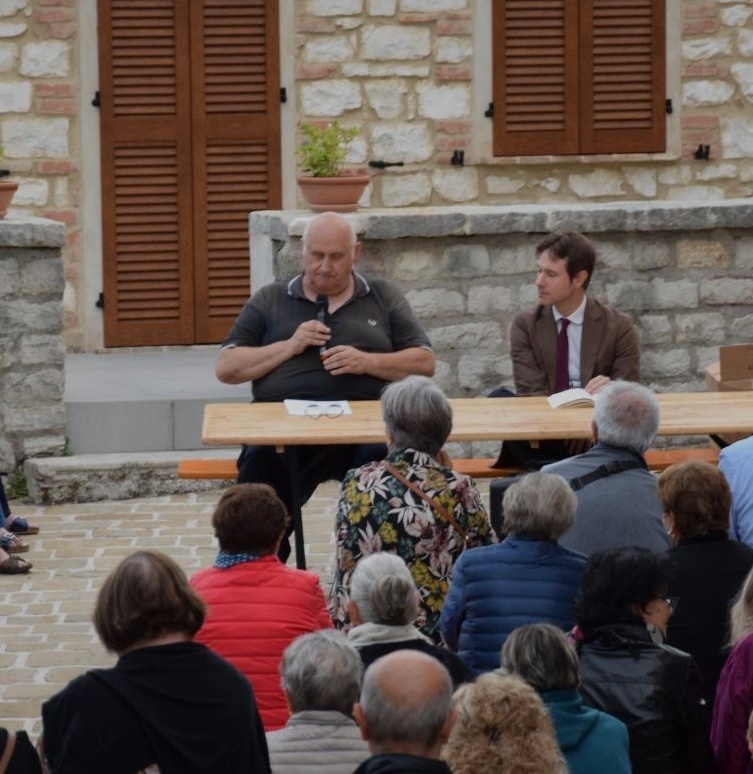 Don Leopoldo Paloni parla al microfono accanto ad Alessandro Gentili durante la conferenza in Piazza Bassa
